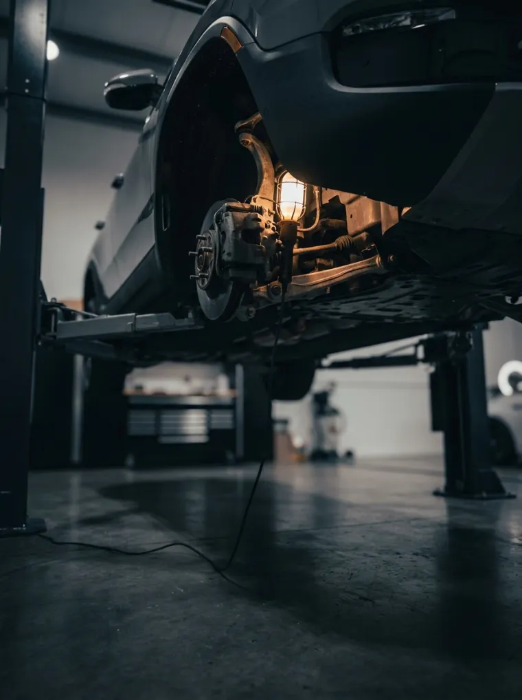 A car on a lift with the underbody lit by an inspection lamp